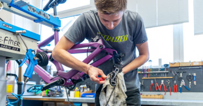 Ein junger Mann löst mit einem Schraubenzieher die Kette eines Fahrrades.