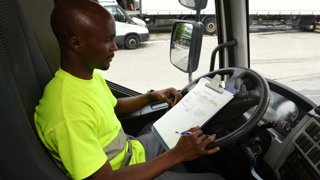 Ein Mann sitzt in einem Lastwagen und studiert seinen Einsatzplan.