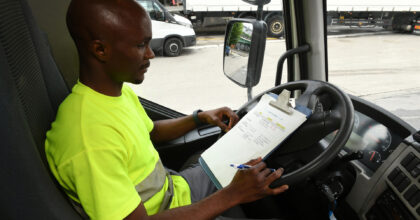 Ein Mann sitzt in einem Lastwagen und studiert seinen Einsatzplan.