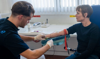 Ein Mann nimmt einer Patientin Blut ab.