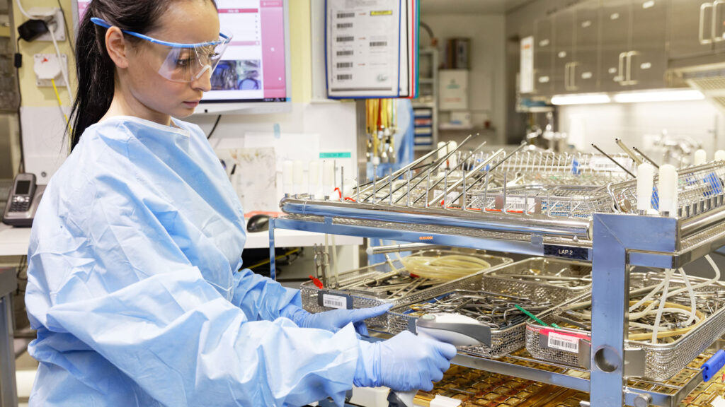 Eine Frau in Schutzkleidung prüft bereitgestellte Medizinprodukte.